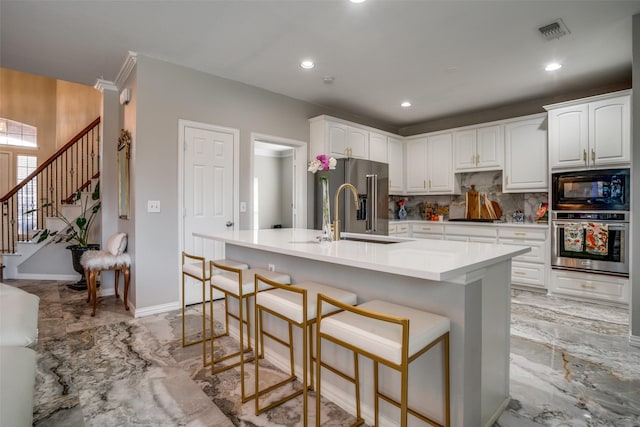 kitchen with white cabinets, marble finish floor, stainless steel appliances, light countertops, and a sink