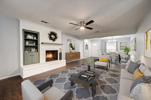 living room featuring built in shelves, visible vents, dark wood-type flooring, a brick fireplace, and baseboards