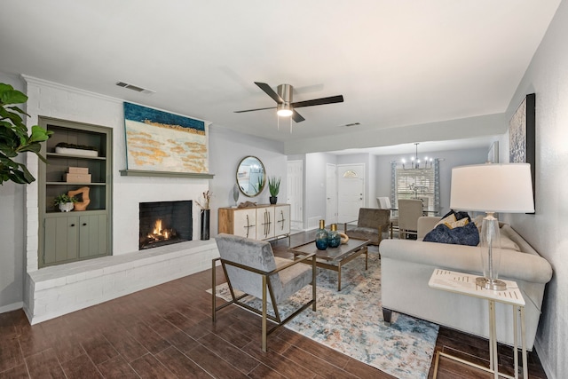 living room featuring visible vents, ceiling fan with notable chandelier, a fireplace, and wood finished floors