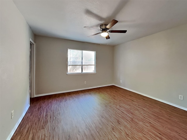 spare room featuring a ceiling fan, baseboards, and wood finished floors