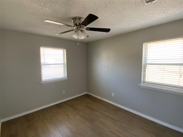 empty room featuring ceiling fan, a textured ceiling, baseboards, and dark wood-style flooring