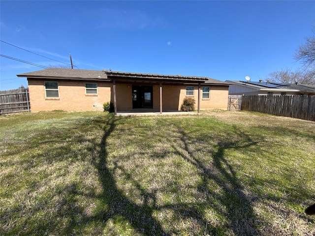 rear view of house with brick siding, a lawn, a patio area, and a fenced backyard