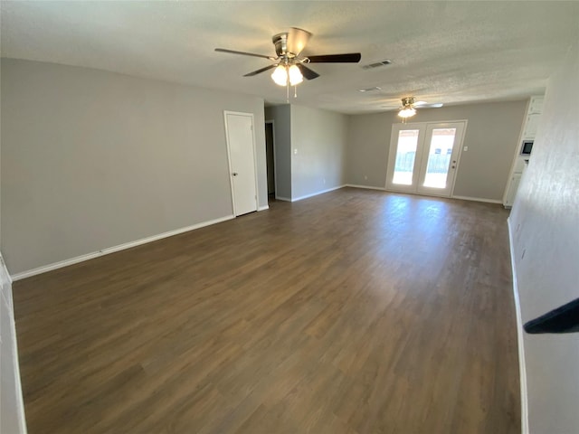 spare room featuring dark wood-type flooring, a ceiling fan, visible vents, and baseboards