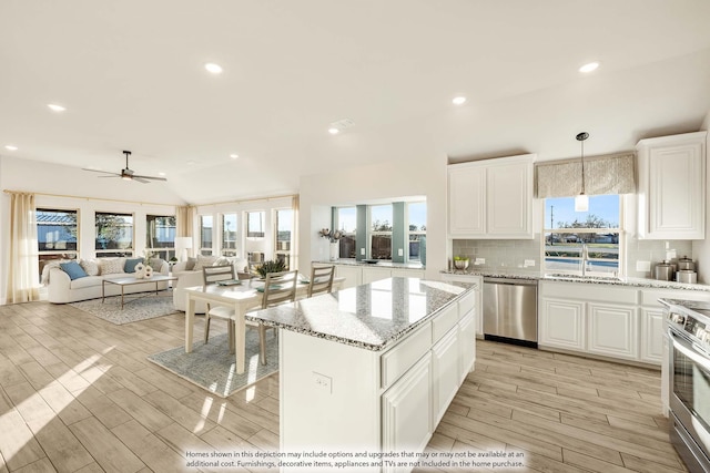 kitchen with pendant lighting, appliances with stainless steel finishes, white cabinetry, a kitchen island, and a sink