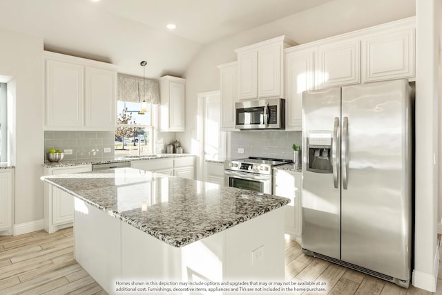 kitchen with a kitchen island, white cabinetry, stainless steel appliances, and pendant lighting