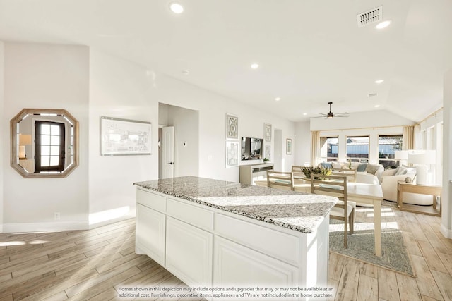 kitchen featuring light stone counters, a kitchen island, light wood-style flooring, and white cabinetry