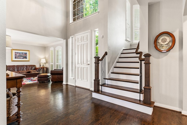 entryway with plenty of natural light, stairs, baseboards, and dark wood finished floors