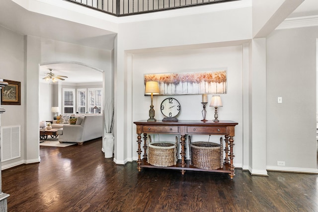 corridor featuring arched walkways, dark wood finished floors, visible vents, and baseboards