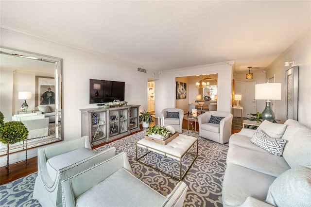 living room featuring ornamental molding, wood finished floors, visible vents, and an inviting chandelier