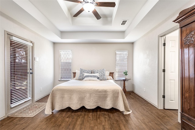 bedroom featuring visible vents, a raised ceiling, a ceiling fan, wood finished floors, and access to outside