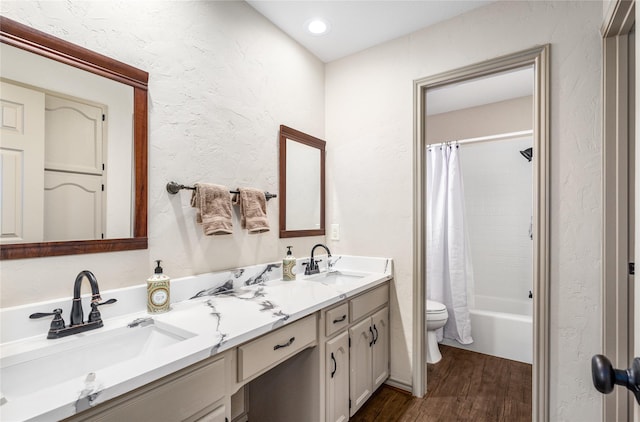 full bath with a textured wall, wood finished floors, a sink, and toilet