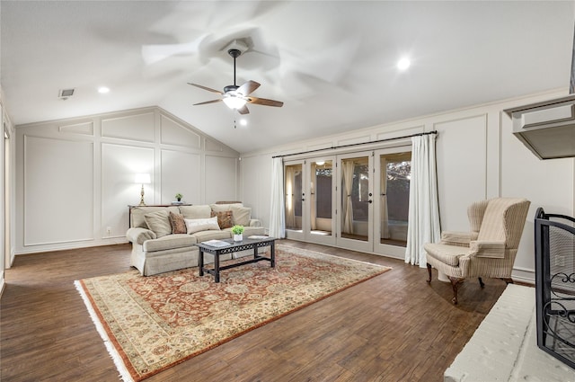 living area with vaulted ceiling, dark wood finished floors, visible vents, and a decorative wall