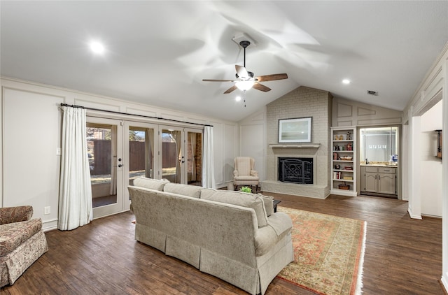 living area featuring lofted ceiling, a fireplace, dark wood-style flooring, and french doors