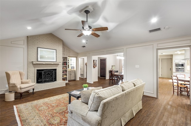 living area featuring visible vents, dark wood-style floors, vaulted ceiling, a fireplace, and a decorative wall