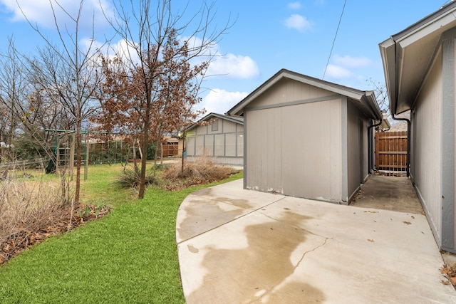 view of side of property featuring a fenced backyard, an outdoor structure, a yard, a storage unit, and a patio area