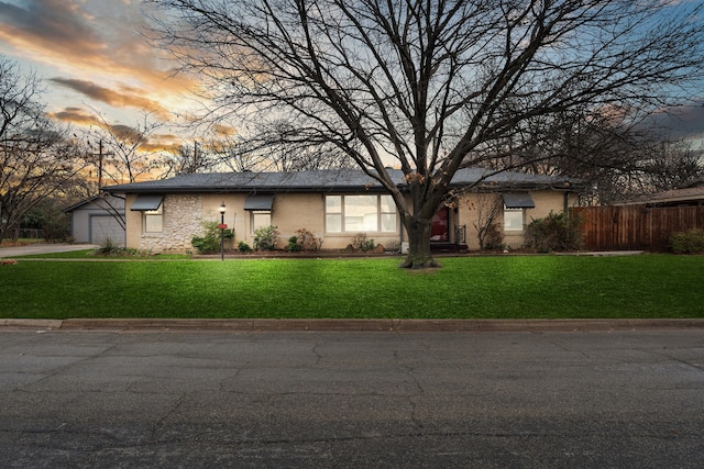 view of front facade featuring an attached garage, fence, and a front lawn