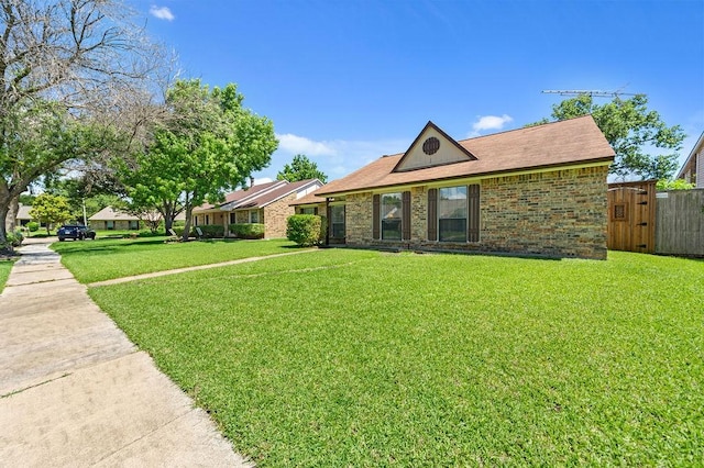 view of front of property with a front yard, brick siding, and fence