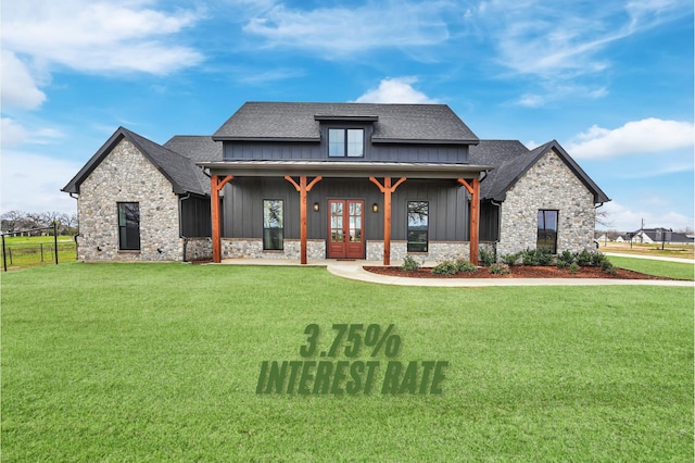 modern farmhouse style home with stone siding, board and batten siding, a front yard, and roof with shingles