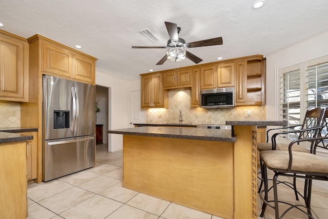 kitchen featuring light tile patterned floors, stainless steel appliances, open shelves, dark countertops, and a kitchen bar