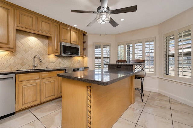 kitchen featuring light tile patterned floors, a breakfast bar area, a center island, stainless steel appliances, and a sink