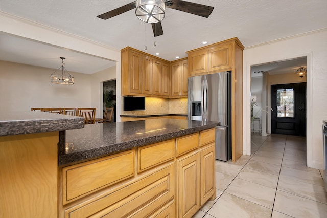 kitchen featuring pendant lighting, light tile patterned floors, backsplash, dark stone countertops, and stainless steel fridge