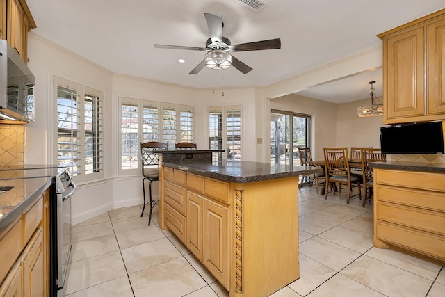 kitchen with dark countertops, light tile patterned floors, appliances with stainless steel finishes, and decorative light fixtures