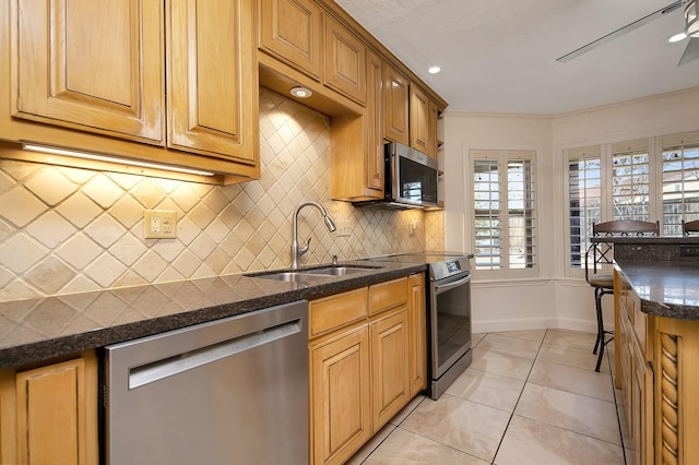 kitchen with light tile patterned floors, decorative backsplash, dark countertops, stainless steel appliances, and a sink