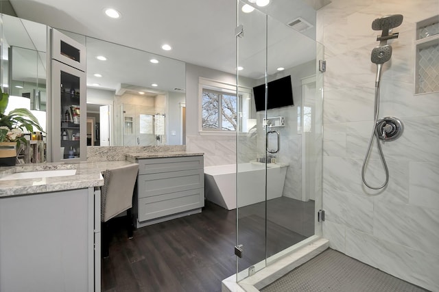 bathroom featuring a freestanding tub, wood finished floors, visible vents, vanity, and a stall shower