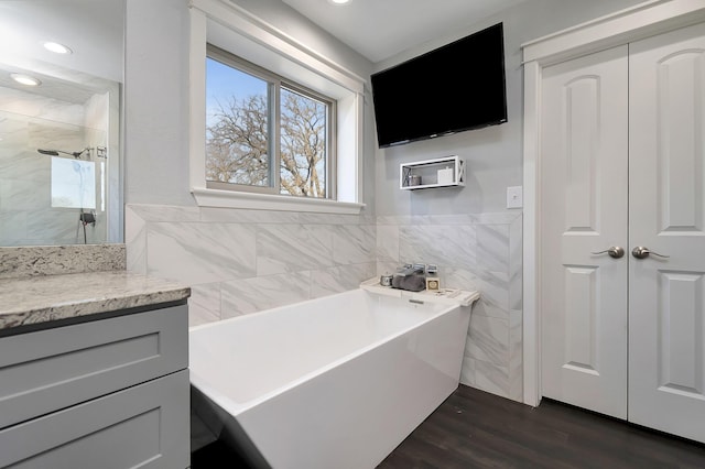 bathroom with tile walls, a soaking tub, a shower stall, vanity, and wood finished floors