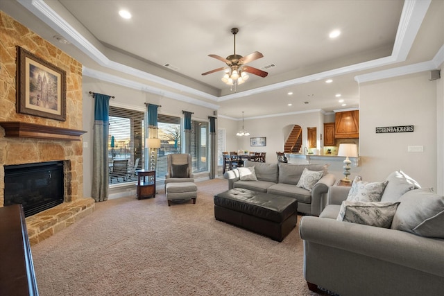 living area with visible vents, a raised ceiling, crown molding, and a stone fireplace