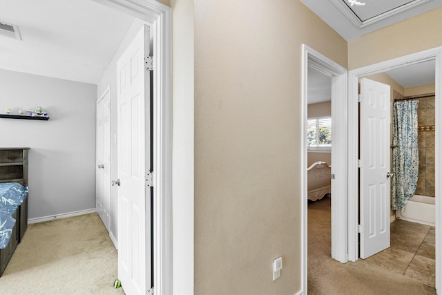 corridor with light colored carpet, visible vents, and baseboards