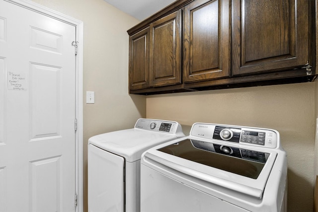 clothes washing area featuring washer and clothes dryer and cabinet space