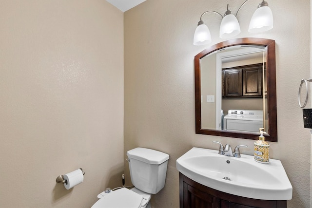 bathroom featuring toilet, washer / clothes dryer, and vanity