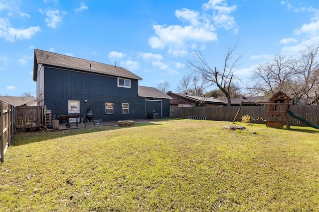 rear view of property featuring a playground, a yard, central air condition unit, a fenced backyard, and a fire pit