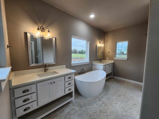 full bath featuring a soaking tub, baseboards, two vanities, and a sink