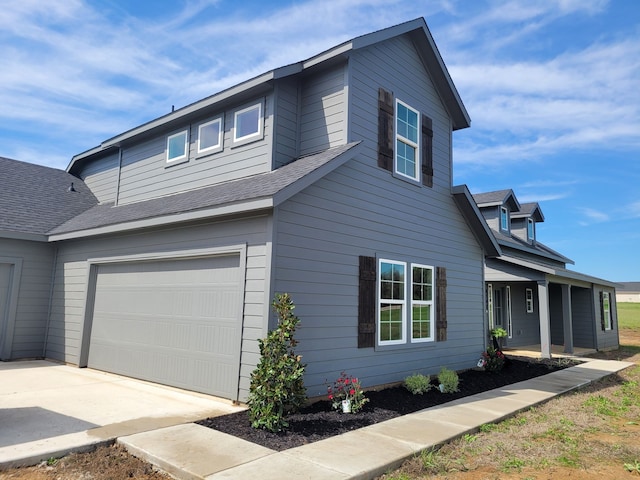 view of front facade with a garage and roof with shingles