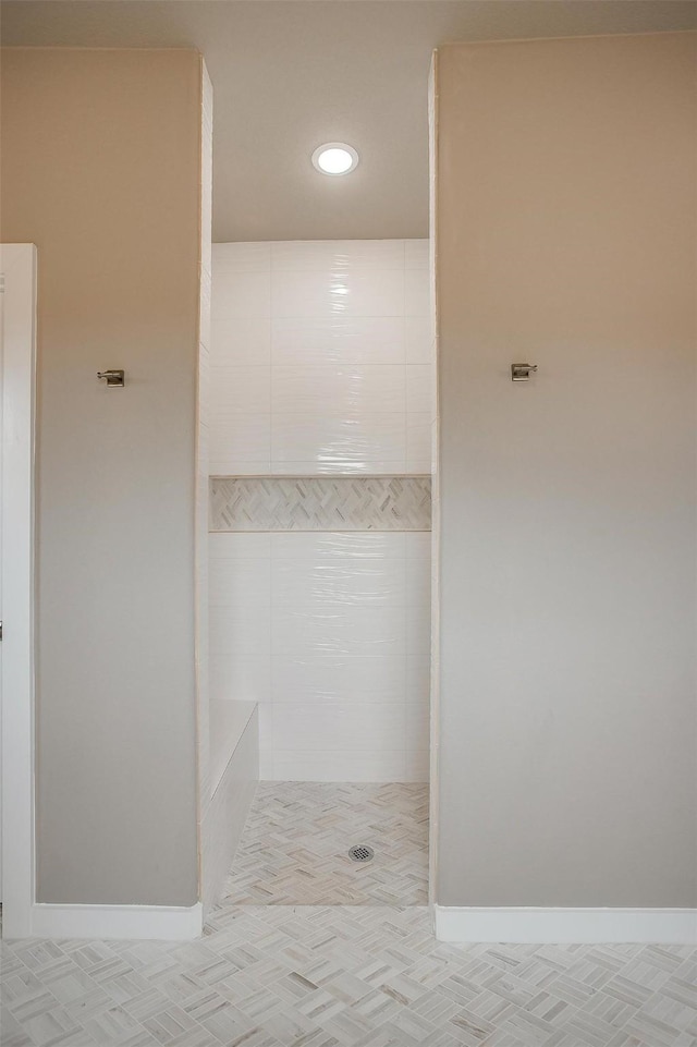 bathroom featuring a tile shower and baseboards