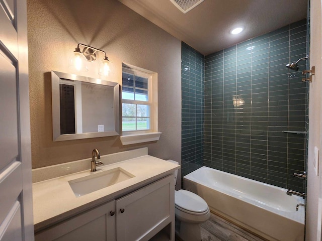 bathroom featuring visible vents, a textured wall, toilet, vanity, and shower / washtub combination