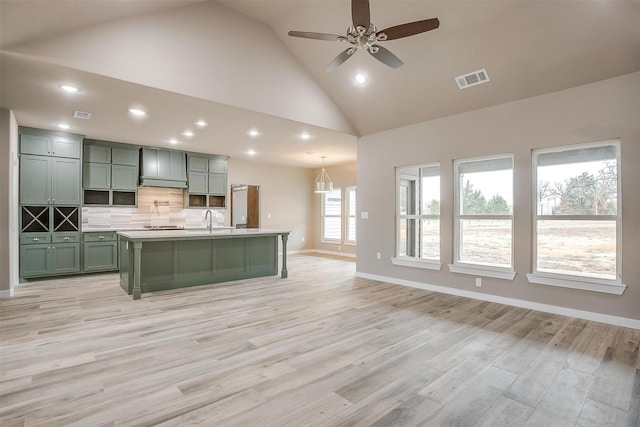 kitchen featuring tasteful backsplash, light countertops, light wood-style floors, green cabinets, and a sink