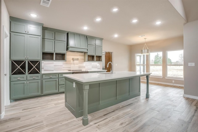 kitchen with visible vents, light countertops, a sink, green cabinetry, and a kitchen bar