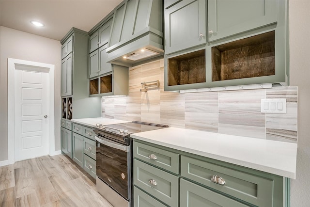 kitchen featuring tasteful backsplash, stainless steel electric stove, custom exhaust hood, light countertops, and green cabinetry