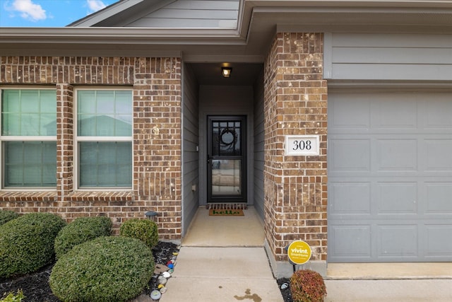 entrance to property with brick siding and an attached garage