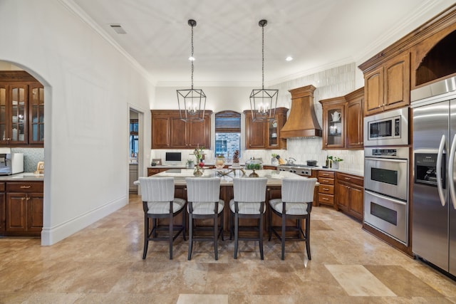 kitchen with light countertops, hanging light fixtures, custom exhaust hood, a center island, and glass insert cabinets