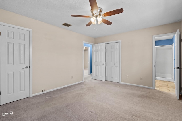 unfurnished bedroom with visible vents, ensuite bathroom, light carpet, a textured ceiling, and baseboards