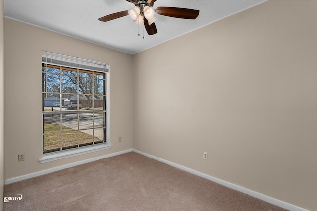 carpeted empty room featuring ceiling fan, a wealth of natural light, and baseboards