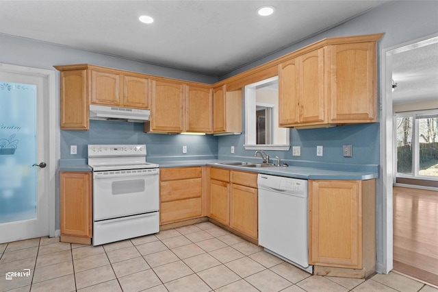 kitchen featuring light countertops, light brown cabinetry, a sink, white appliances, and under cabinet range hood