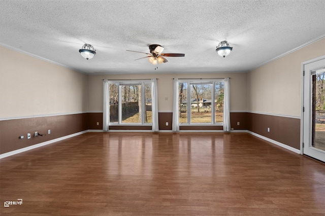 interior space with a healthy amount of sunlight, a wainscoted wall, and dark wood finished floors