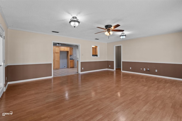 unfurnished room featuring a ceiling fan, ornamental molding, light wood-style flooring, and a textured ceiling