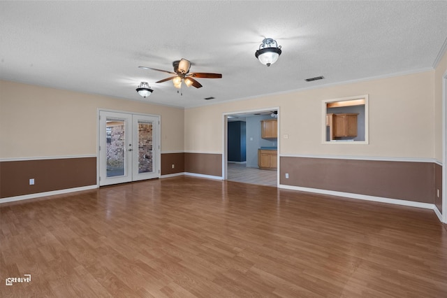 unfurnished room with french doors, a ceiling fan, ornamental molding, a textured ceiling, and wood finished floors