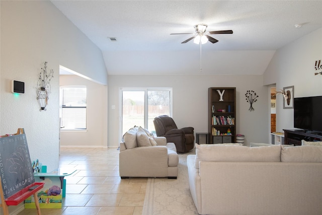 living area featuring light tile patterned floors, ceiling fan, visible vents, and vaulted ceiling